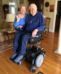 Couple at home with motorized chair.